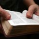 Young man reading the Bible - closeup on hands with open book