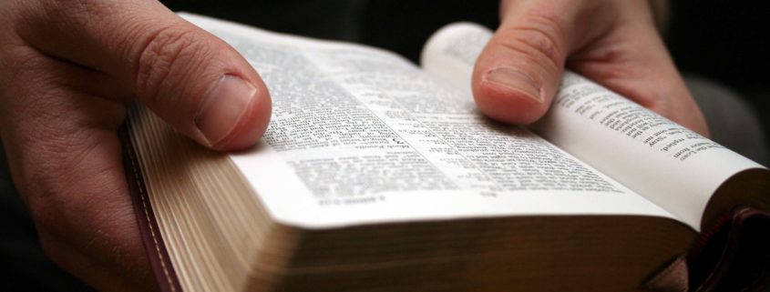Young man reading the Bible - closeup on hands with open book